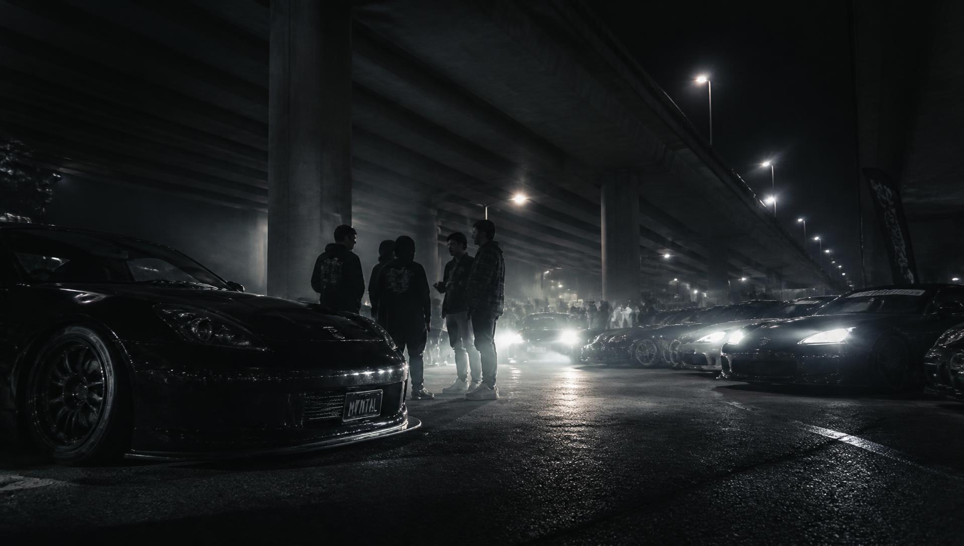 Night car meet with headlights cutting through the dark